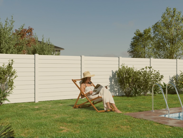 Femme dans son transat lisant une revue dans son jardin à coté de la piscine devant une clôture haut de gamme en aluminium MyDoorling de couleur blanc signalisation